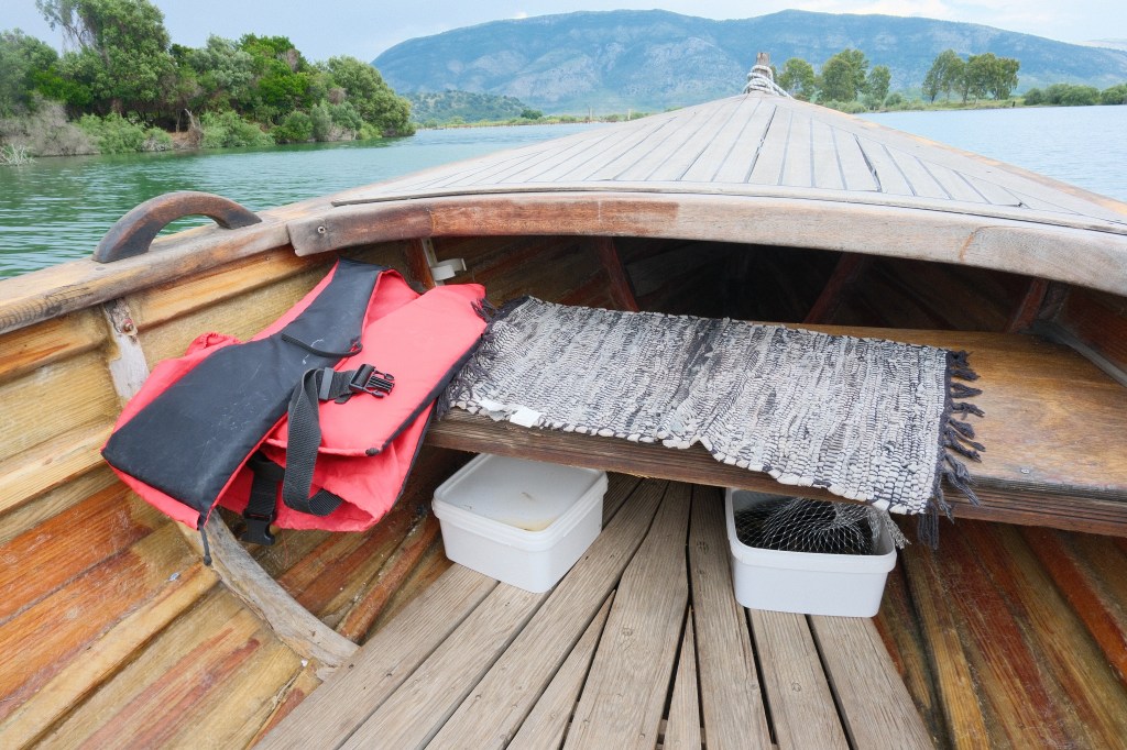 Image of the front of the boat, with a rug on the seat, a life jacket and some mussels in a box underneath.
