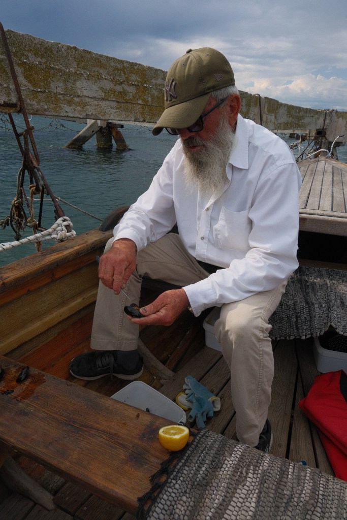 Photo of the captain preparing the fresh mussel with lemon on the boat, next to the mussel farm.